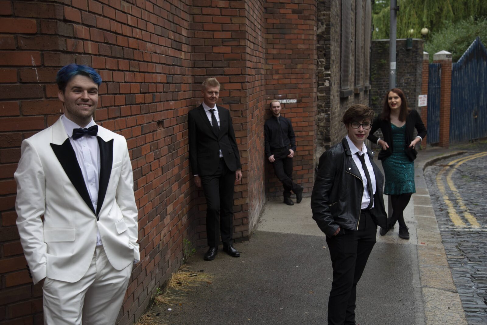 Five members of Token Straight stand spread out down a lane while dressed in formal wear