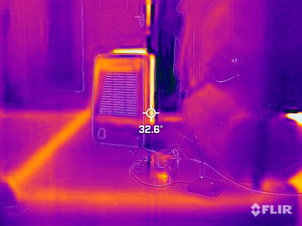 Thermographic image of dehumidifier in room. The photographic image has distorted colour in purples and oranges and has a central target point on it marked 32.6 degrees.