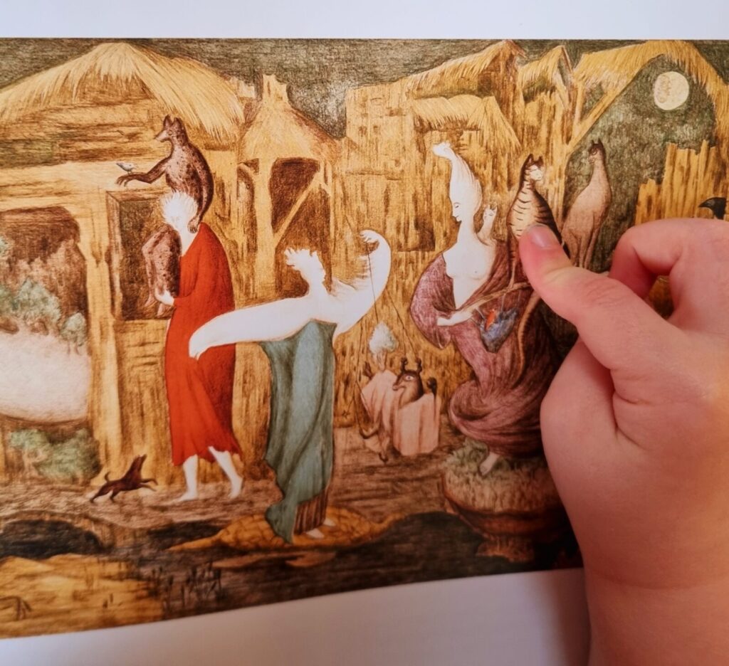 The image shows a page of a book with a painting by Leonora Carrington, and a child's hand on top of the image. The painting includes three spectral figures in front of a background of thatched buildings. They interact with various animals. The child’s hand points to a cat-like creature held by one of the figures.