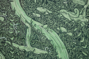 A close-up of an artwork detail on the Project billboard. The artwork shows a green and black drawing of water overflowing from Holy Wells. Fish and strange creatures are appearing from the water, surrounded by dense foliage. Nestled in the top right corner is a street sign for Sráid Thobar Phádraig/Nassau Street.